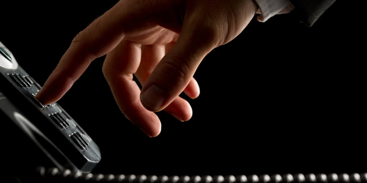 Businessman's hand dialing a phone pad on a black background